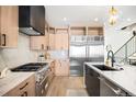 Modern kitchen with stainless steel appliances, light wood cabinets, and stone countertops at 4238 Zuni St, Denver, CO 80211