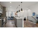 Open-concept kitchen featuring a large island with seating, modern lighting, and stainless steel appliances at 2127 Alcott Way, Broomfield, CO 80023