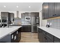 Modern kitchen with stainless appliances, dark cabinetry, large island with quartz countertops, and backsplash at 17851 Herrera Dr, Parker, CO 80134