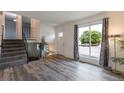 Open-concept living area with gray wood flooring, stairs with black metal railing and large window at 2493 S Kalispell Cir, Aurora, CO 80013