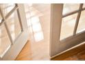 Sunlight streams through open French doors onto gleaming hardwood floors, offering an inviting transition between spaces at 3231 Oak St, Wheat Ridge, CO 80033