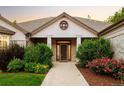 Inviting entryway featuring a dark wood door, sidelights, brick columns, and manicured landscaping at 3231 Oak St, Wheat Ridge, CO 80033