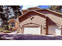 A close-up of the three-car garage featuring a stucco exterior and the house number displayed above the main garage door at 19850 Indian Summer Ln, Monument, CO 80132