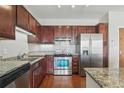 Stylish kitchen features granite counters, stainless steel appliances, dark wood cabinets, and tile backsplash at 13598 Via Varra # 105, Broomfield, CO 80020