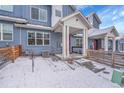 View of a blue townhome with a red door and white trim during a snowy day at 6211 W 28Th Ct, Wheat Ridge, CO 80214