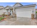 Exterior view of this home with its attached two-car garage and stone facade and beautiful lawn at 9674 Fox Den Dr, Littleton, CO 80125