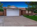 Exterior of the house with two car garage and concrete driveway and lawn at 12906 Cherry Way, Thornton, CO 80241