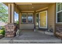 Inviting covered front porch featuring stone pillars, a sunny yellow door, and charming decorative accents at 7580 S Biloxi Ct, Aurora, CO 80016