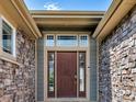 Inviting front door with sidelights and transom window, framed by stone and neutral siding at 413 N De Gaulle Ct, Aurora, CO 80018
