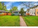 Charming single story home has a well maintained lawn, mature trees and a walkway to the front door at 1241 Wabash St, Denver, CO 80220