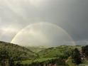 Dramatic landscape featuring a vibrant double rainbow arcing over rolling green hills and valleys at 6057 Red Hill Rd, Boulder, CO 80302