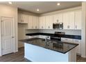 Modern kitchen featuring white cabinets, stainless steel appliances, and a dark countertop island with a sink at 1613 Bloom St, Brighton, CO 80601
