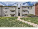Exterior view of apartments with light-colored siding, multiple balconies and landscaped lawn at 10150 E Virginia Ave # 301, Denver, CO 80247