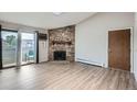 Cozy living room with stone fireplace, sliding glass door and light laminate flooring at 10150 E Virginia Ave # 301, Denver, CO 80247