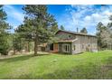Gray two-story home with a well-kept lawn surrounded by trees, and a convenient two-car garage, offering picturesque curb appeal at 8851 Blue Creek Rd, Evergreen, CO 80439