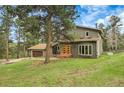 Charming gray home with a lawn surrounded by evergreen trees, boasting a beautiful and welcoming entrance with a two-car garage at 8851 Blue Creek Rd, Evergreen, CO 80439