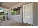 Close-up of a cozy front porch with brick accents, a white door, and views of the lush green surroundings at 1120 S Harrison St, Denver, CO 80210