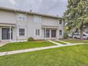 Exterior of the townhomes featuring well-maintained lawns and muted light gray siding at 1932 S Oswego Way, Aurora, CO 80014