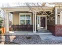 Charming front porch with dark wood door, brick accents, and white pillars at 1280 Galactic Pl, Castle Rock, CO 80108