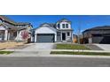 Beautiful two-story home with white siding, a gray garage door, and a well-maintained lawn at 6071 Caribou Dr, Brighton, CO 80601