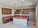Spacious kitchen featuring wood cabinets, an island, and pendant lighting, awaiting final touches at 6071 Caribou Dr, Brighton, CO 80601