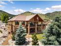 Two-story exterior elevation featuring brick accents and a walkout basement, all enhanced by the backdrop of green mountain views at 6170 Falcon Ln, Morrison, CO 80465