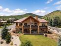Beautiful two-story exterior elevation with brick accents, a cozy balcony, luscious green grass and mountain views at 6170 Falcon Ln, Morrison, CO 80465