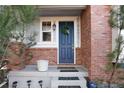 Close-up of a stylish blue front door with a wreath, brick surround, and landscaped entrance at 9690 E 5Th Ave, Denver, CO 80230