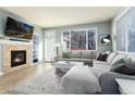 Bright living room featuring a cozy fireplace, large windows, and a comfortable gray sectional sofa and rug at 9690 E 5Th Ave, Denver, CO 80230