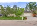 Beautifully landscaped front yard featuring lush green grass, mature trees, and a two car garage at 2871 Humboldt Cir, Longmont, CO 80503