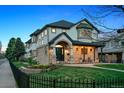 Elegant two-story home with a stone facade, covered front porch, manicured lawn, and wrought iron fence at 2500 S Clayton St, Denver, CO 80210
