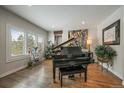 Sophisticated living room with a grand piano, hardwood floors, and natural light at 1366 Killington Ct, Evergreen, CO 80439