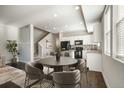 Open dining area with a modern table set, flowing seamlessly into a bright kitchen with sleek, black appliances at 16069 E Elk Dr, Denver, CO 80239