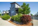 Modern two-story home with a gray exterior, complemented by lush landscaping, bushes, and a well-maintained yard at 16069 E Elk Dr, Denver, CO 80239