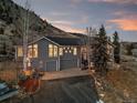 Stunning exterior elevation of gray home with mature trees and sunset views at 31969 Robinson Hill Rd, Golden, CO 80403