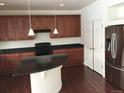 Well-lit kitchen featuring dark cabinets, black countertops, stainless steel appliances, and dark hardwood flooring at 4995 S Algonquian Way, Aurora, CO 80016