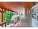Side porch featuring a brick facade, wooden floorboards and railings with a view of the lawn and white picket fence at 1101 Dakin St, Denver, CO 80221