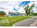 Charming blue ranch home featuring a well-manicured lawn and inviting curb appeal at 1853 Burton St, Strasburg, CO 80136
