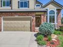 Close-up showcasing the brick exterior, garage door, and landscaped entry of the charming two-story home at 6366 Umber Cir, Arvada, CO 80403