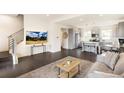 This living room features dark floors, a view of the stairs and kitchen, with a TV on the wall at 5668 Galena St, Denver, CO 80238