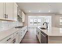 Bright kitchen with white cabinets, stainless steel appliances, and hardwood floors at 25284 E Warren Pl, Aurora, CO 80018