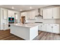 Bright kitchen features white cabinets, an island, stainless steel appliances, and hardwood floors at 25284 E Warren Pl, Aurora, CO 80018