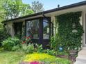 Charming home featuring a manicured lawn, white brick, lush greenery climbing on the walls, and black bay window at 280 E 11Th Ave, Broomfield, CO 80020