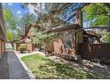 Exterior view of home showing mature trees, private patio area, and wood siding at 8010 Holland Ct # D, Arvada, CO 80005