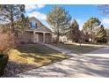 Charming home featuring mature trees, manicured lawn, brick accents, and inviting front porch at 7944 E Lowry Blvd, Denver, CO 80230