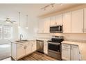 Bright kitchen featuring white cabinets, stainless steel appliances, and wood flooring at 12898 King St, Broomfield, CO 80020