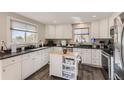 Bright kitchen with white cabinets, dark countertops, and a butcher block island at 18128 Sage Brush Way, Brighton, CO 80603