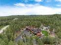 Beautiful aerial view of a luxury home on acreage nestled in the forest with lush landscaping at 44 N Big Meadow Trl, Franktown, CO 80116