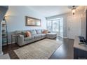 Bright living room with a comfortable gray sofa, hardwood floors, and a large bay window at 4927 Tarcoola Ln, Highlands Ranch, CO 80130