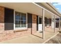 Close up on a brick porch with white pillars, black shutters and white front door at 9161 W Hialeah Pl, Littleton, CO 80123